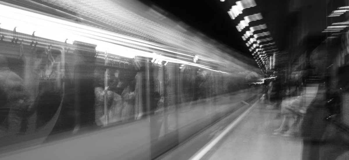Black and white motion blur of a subway train in an underground station, capturing urban energy.